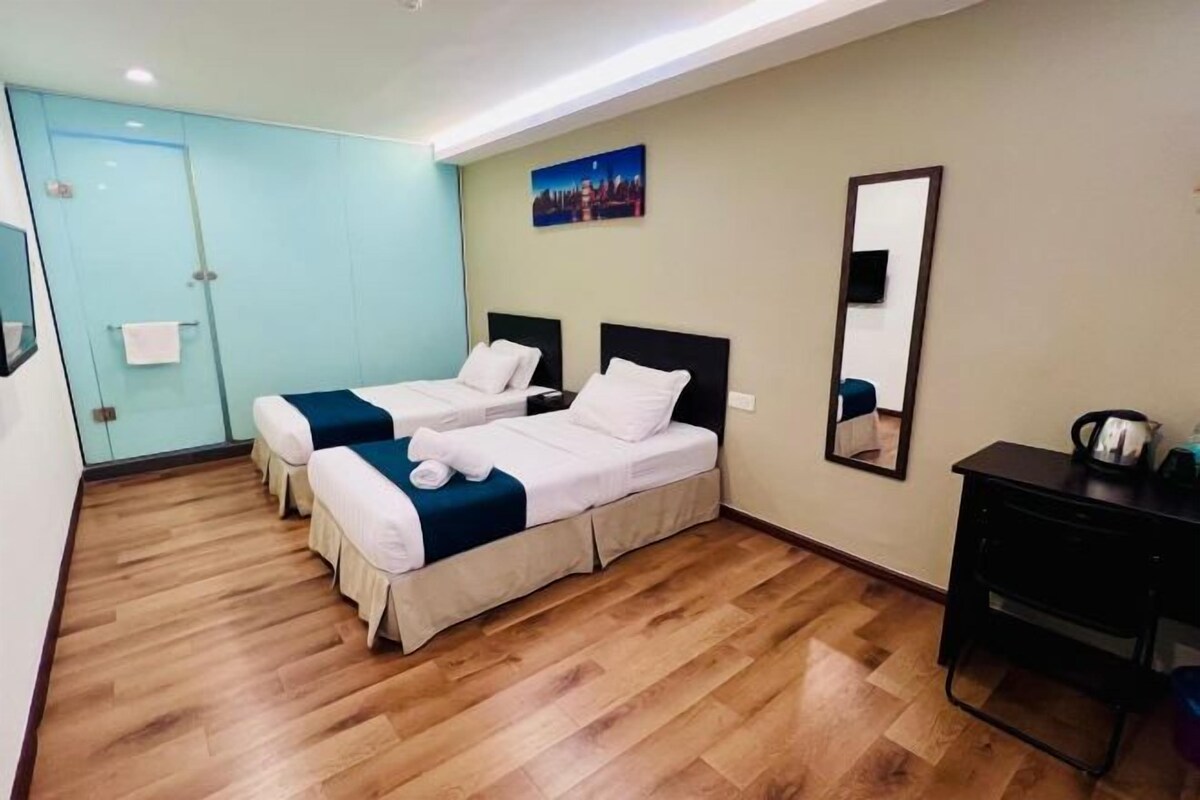 Habitación de hotel con dos camas, piso de madera, un espejo y un escritorio.