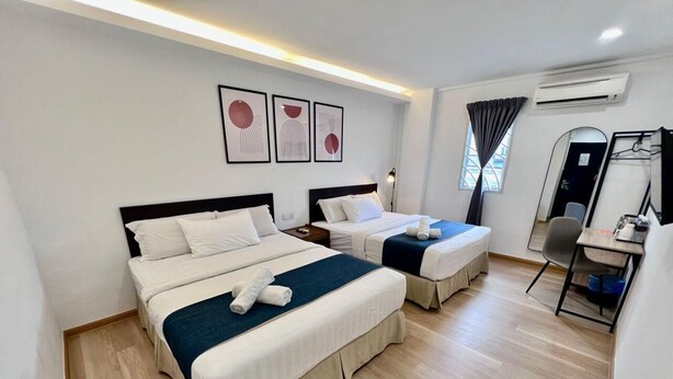 Habitación de hotel con dos camas, un escritorio, una silla y un espejo.