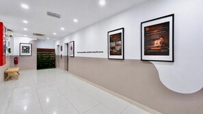 A hotel corridor with framed promotional posters on the walls, a fire extinguisher, and a wooden bench. - Orange Hotel Kota Kemuning @ Shah Alam (Shah Alam)