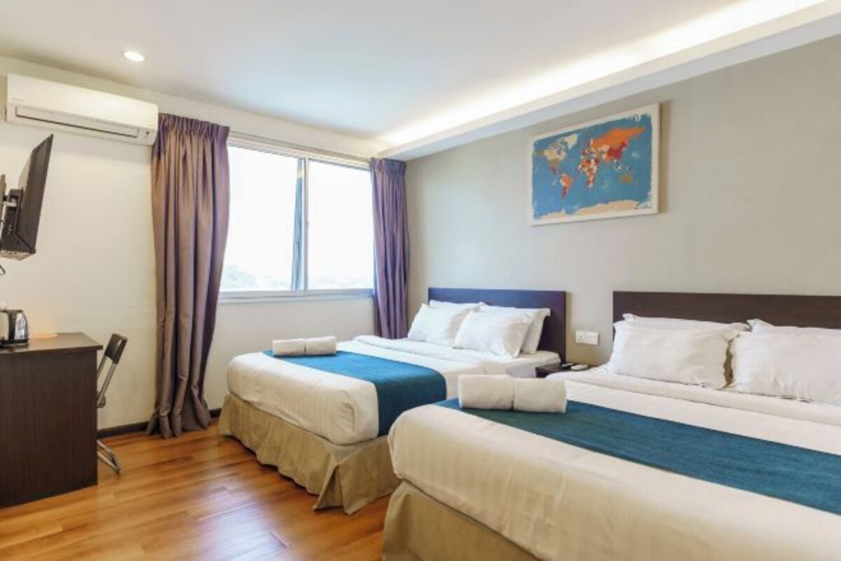 A hotel room with two beds, a desk, and a large window with curtains.