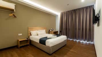 Una habitación de hotel con cama, mesita de noche y televisor montado en la pared.