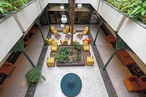 A rooftop lounge with yellow chairs, a central planter with greenery, and hanging lights. - Universal (Terras de Bouro)