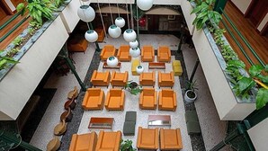A hotel lobby with multiple seating areas, hanging light fixtures, and potted plants. - Universal (Terras de Bouro)