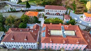 An aerial view of a residential area with buildings, roads, and a river. - Universal (Terras de Bouro)