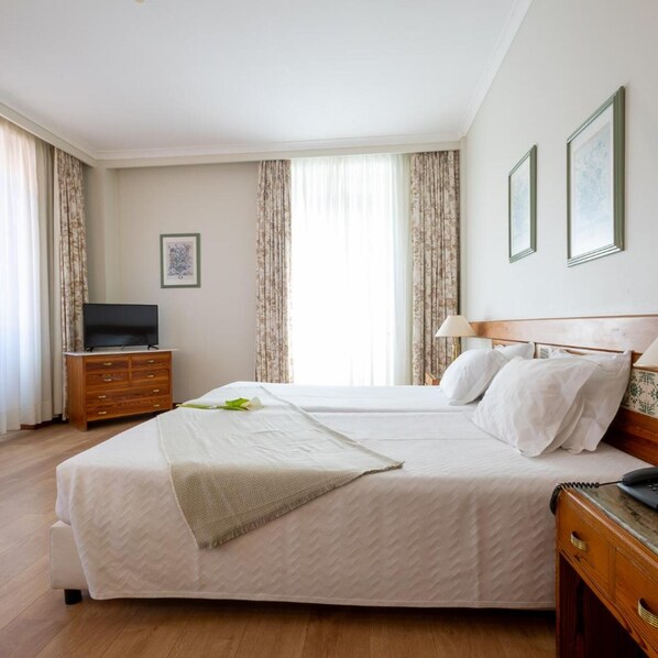 A hotel room with a large bed, a TV, a dresser, and a lamp. - Universal (Terras de Bouro)