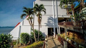 A modern building with a white facade, a balcony, and a view of the sea.