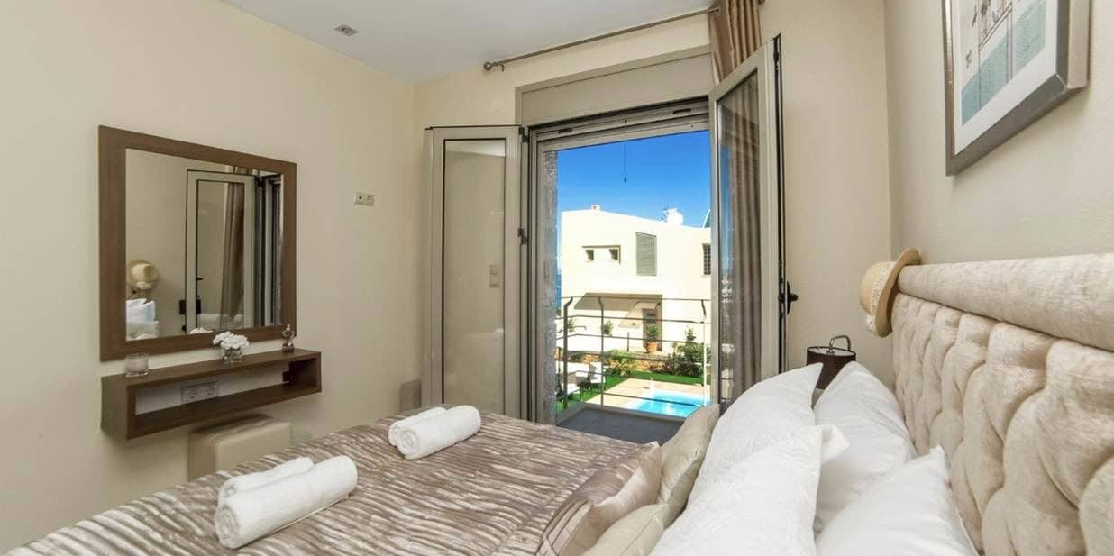 Habitación de hotel con cama, baño con espejo y vista a una piscina.
