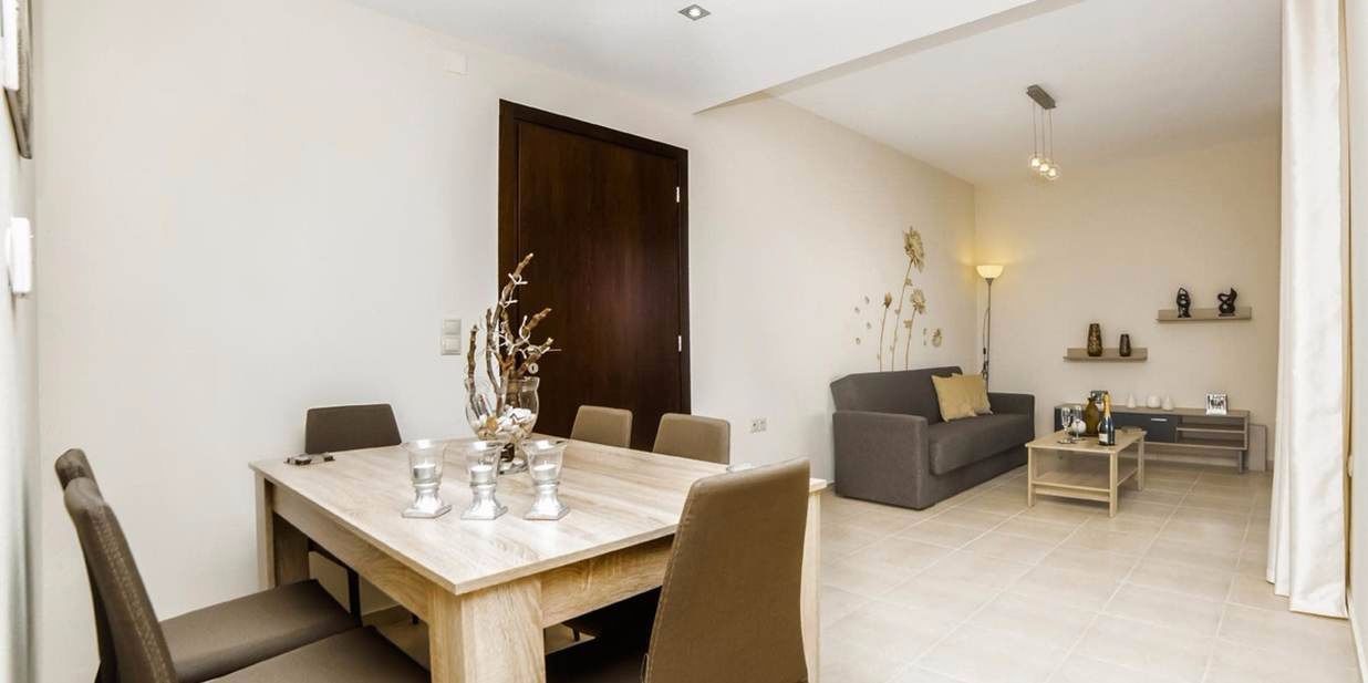 A modern living room with a dining area, featuring a wooden table, chairs, a sofa, and a coffee table.