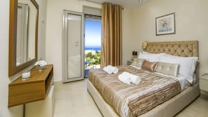 Una habitación de hotel con cama, mesita de noche, espejo, ventana con cortinas y vistas al exterior.