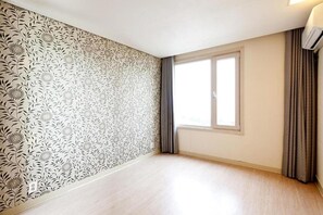 A room with a patterned wallpaper, a large window with curtains, and a light-colored floor. - Sono Belle Byeonsan (Buan)