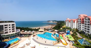 A resort with a large swimming pool, water slides, and beachfront views.