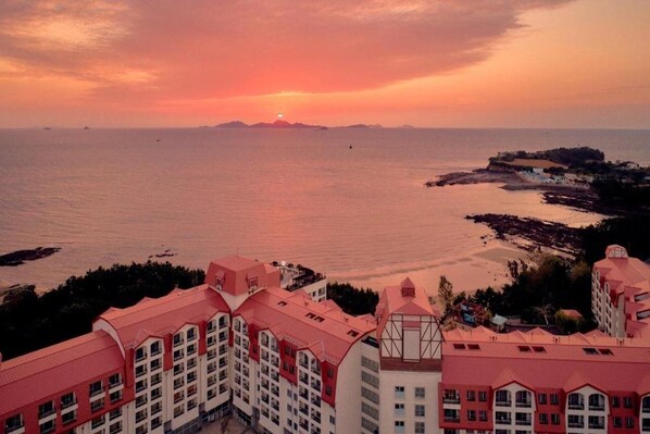 A coastal hotel with multiple buildings, a view of the sea, and a sunset in the background. - Sono Belle Byeonsan (Buan)