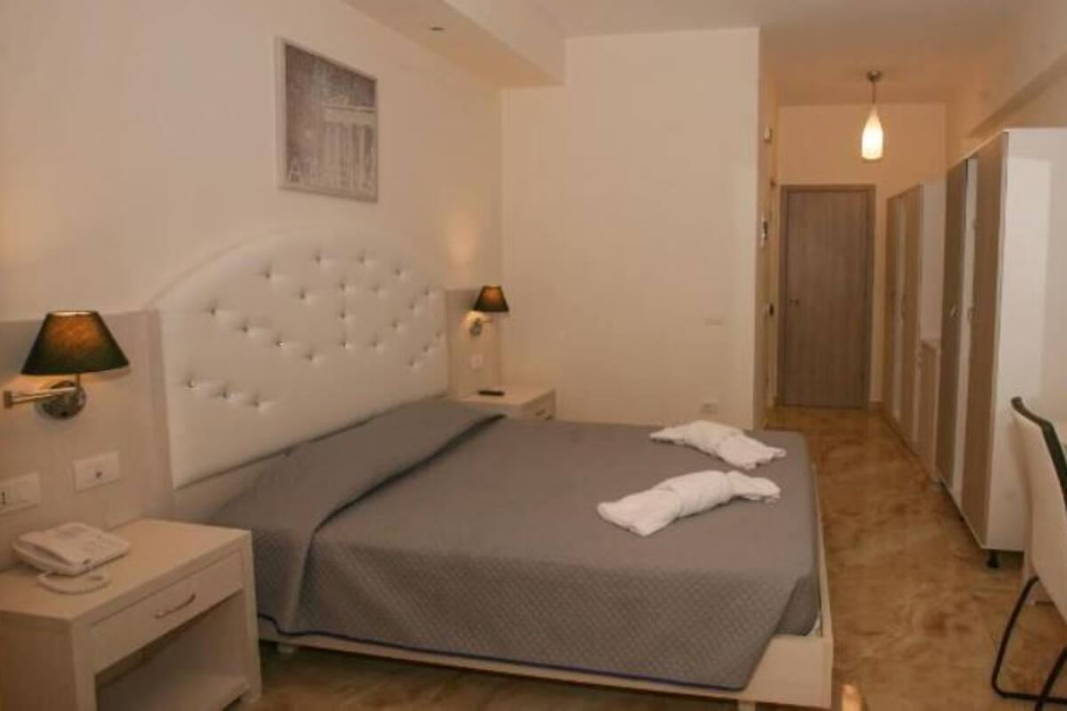 A bedroom with a bed, bedside lamps, a desk, and a chair.