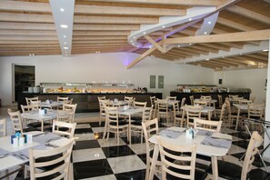 A restaurant with a checkered floor, wooden tables and chairs, and a bar area with a counter. - Saint George Palace (Corfu)
