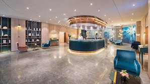 A modern lobby with a central reception desk, seating areas, and a large wall mural.