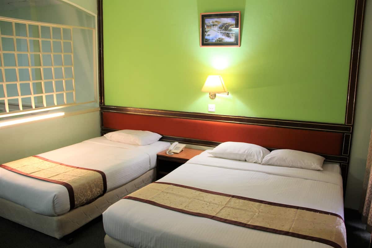 Una habitación de hotel con dos camas, una mesita de noche con lámpara y un cuadro en la pared.