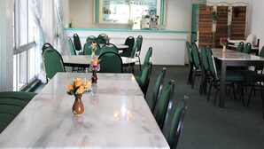A dining area with green chairs, a marble table, and a vase with flowers. - Miri Hotel (Miri)