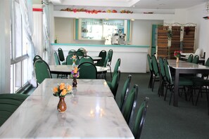 Un comedor con sillas verdes, una mesa de mármol y un florero con flores.