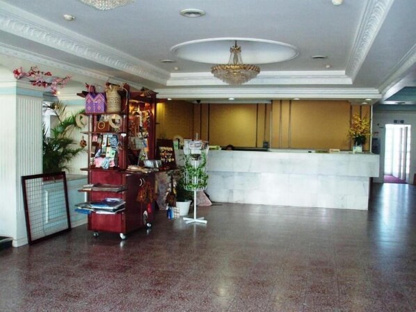 Un vestíbulo con mostrador de recepción, una máquina expendedora roja y una planta decorativa.