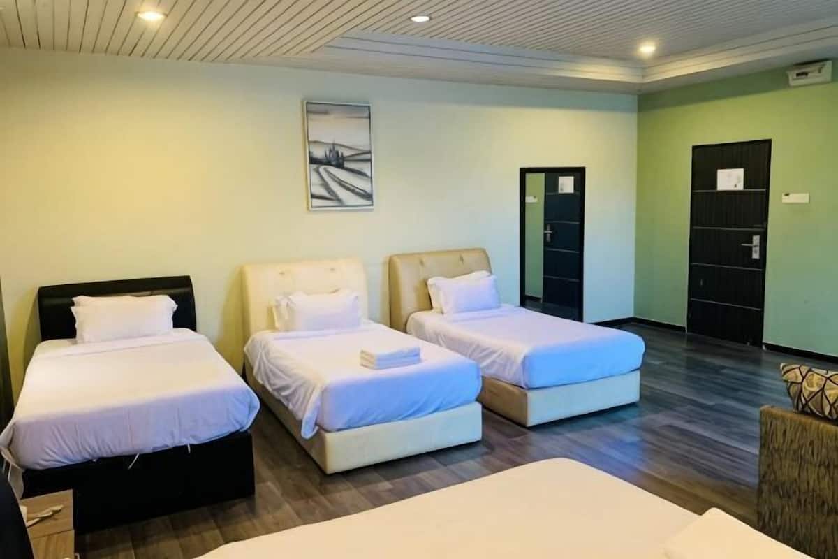 A hotel room with three beds, a painting on the wall, and a door with a sign.