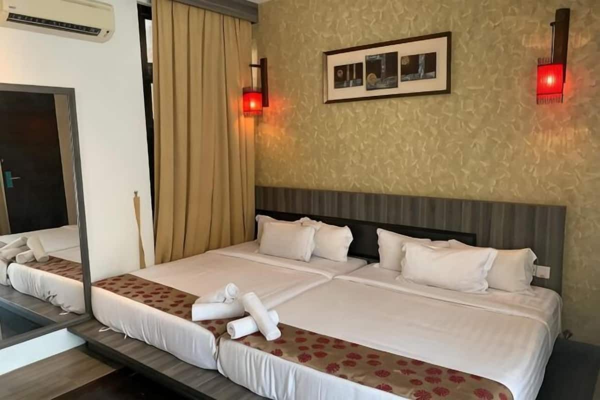 A hotel room with a large bed, a mirror, a framed picture on the wall, and two wall-mounted lights.