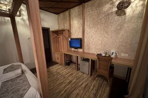 A bedroom with a bed, a desk with a computer, a television, and a wardrobe.