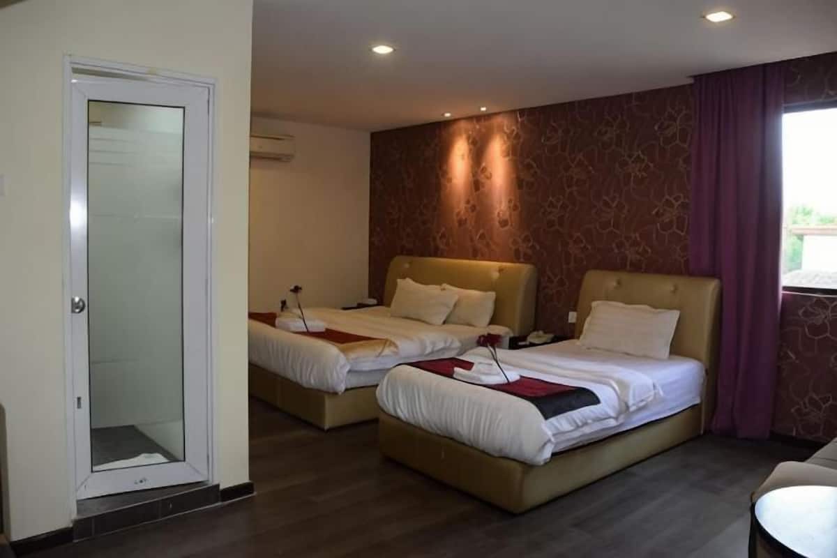 A hotel room with two beds, a door, and a window with curtains.