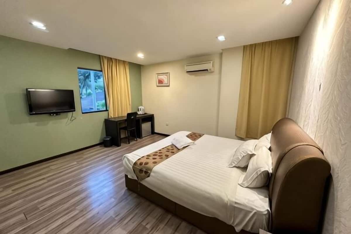 A hotel room with a bed, a desk, a chair, a television, and a window with curtains.