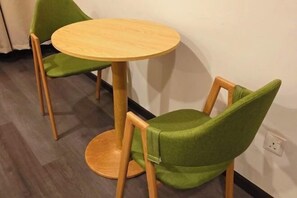 A small round wooden table with two green chairs. - I Garden Hotel (Ipoh)