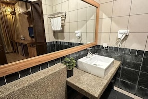 A bathroom with a sink, mirror, towel rack, and a plant.