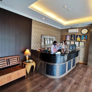 A reception area with a counter, a bench, a lamp, and framed pictures on the wall.