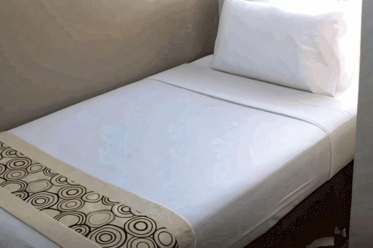 Un lit simple avec une couvre-lit à motifs et un oreiller.