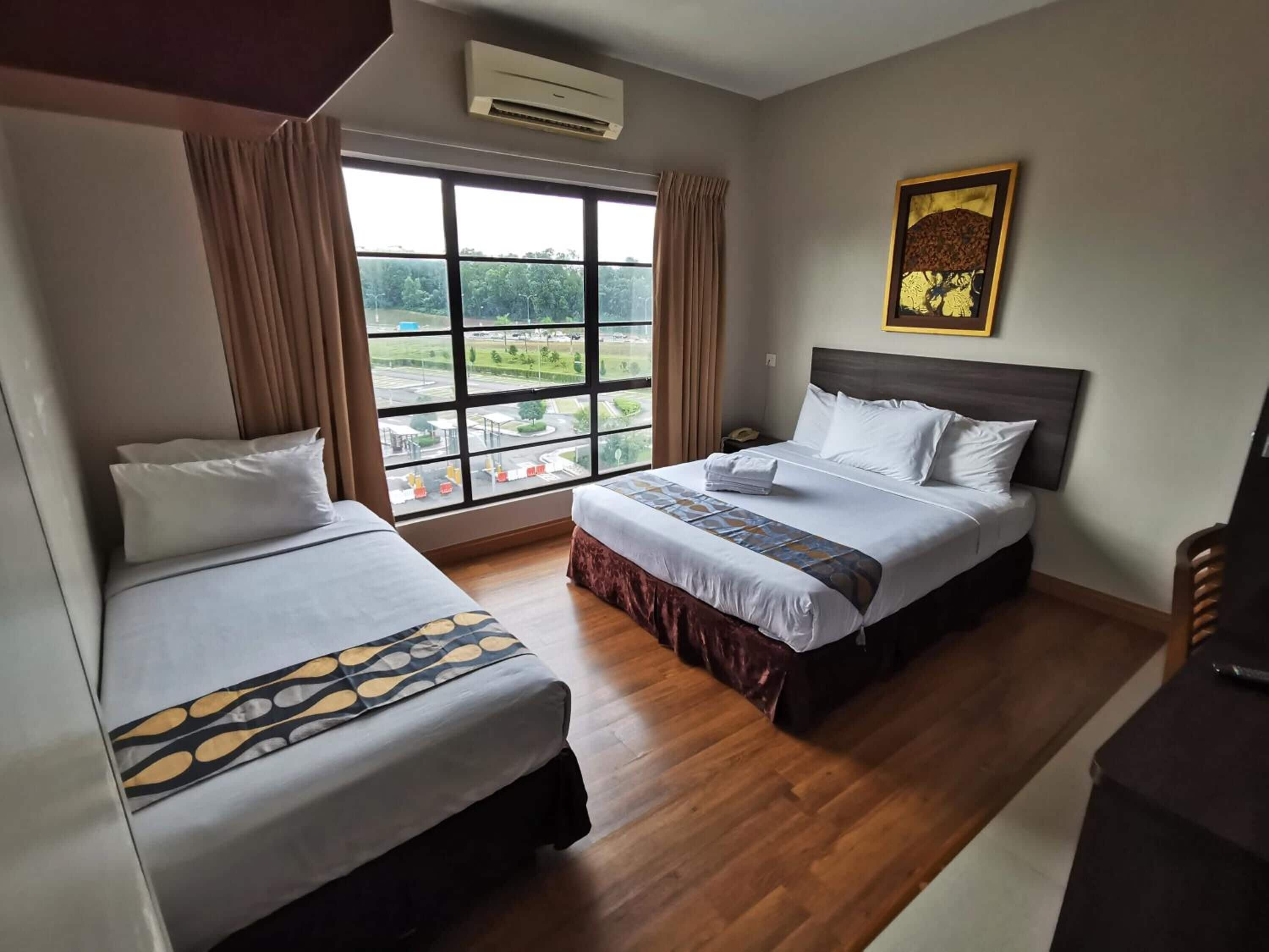Una camera d'albergo con due letti, una grande finestra vista, un condizionatore d'aria e un quadro appeso al muro.