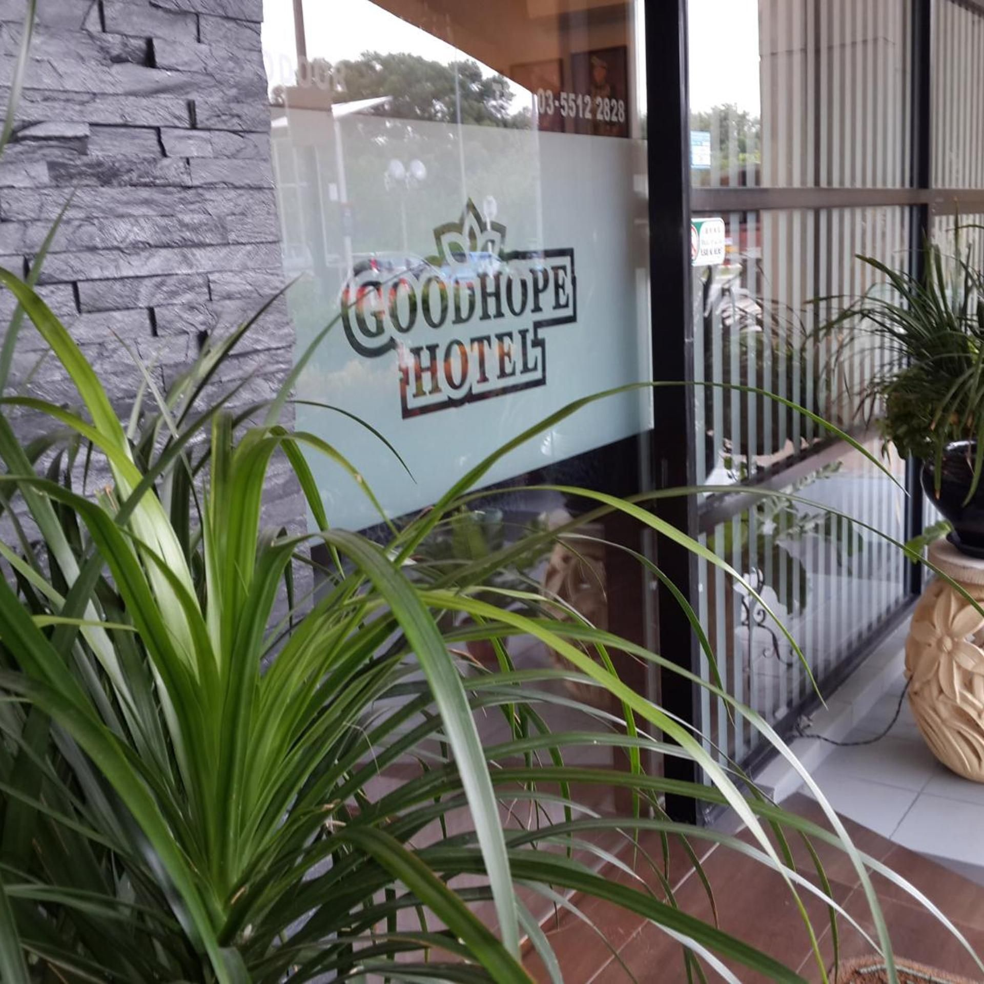 A Good Hope Hotel sign with a stone wall and potted plants.