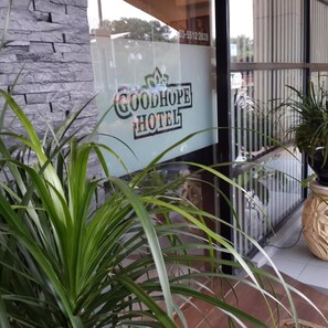 A Good Hope Hotel sign with a stone wall and potted plants.