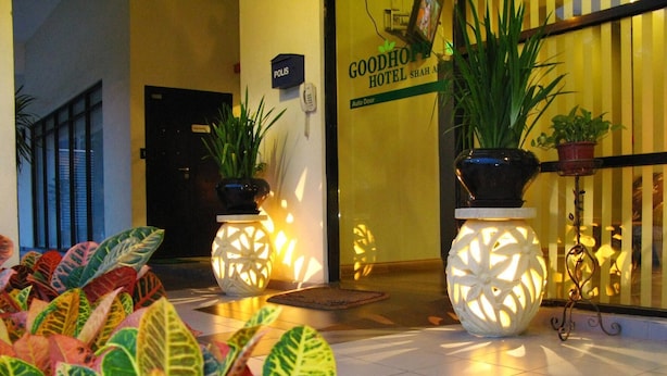 L’entrée d’un hôtel, agrémentée de plantes en pot, un comptoir d’accueil et une enseigne indiquant le « Good Hope Hotel ».