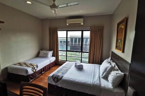 Two single beds with white linens, a desk, and chair, plus a window with a view.