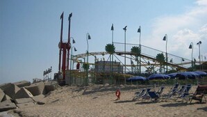 Une plage avec des montagnes russes, des chaises longues, des parasols et un cercle de sauvetage.