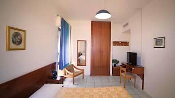 Ein Hotelzimmer mit einem Bett, einem Schreibtisch, einem Sessel, einem Fernseher und einem Kleiderschrank.