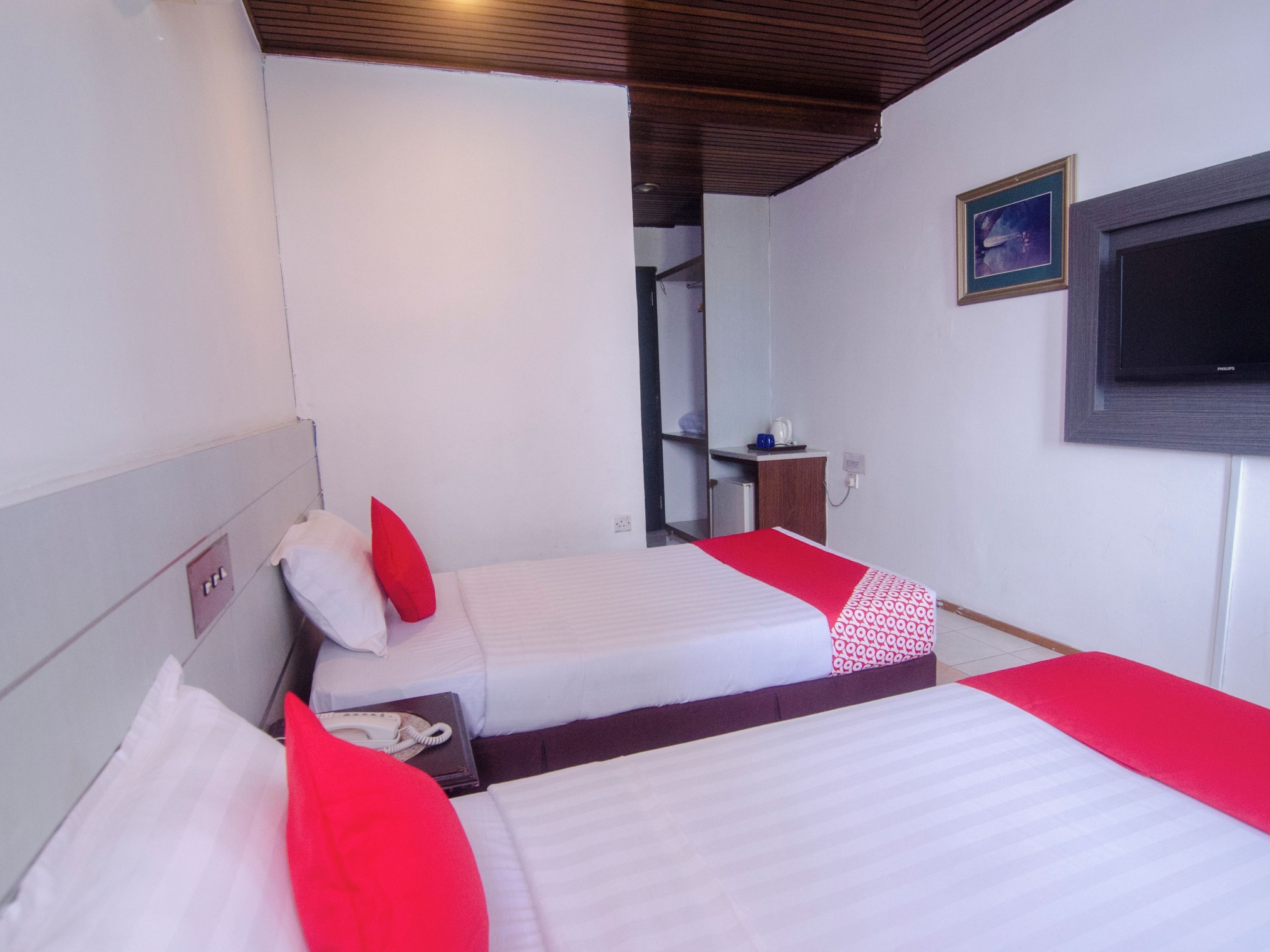 A hotel room with two beds, a TV, and a small kitchenette.