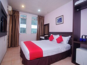 A hotel room with a bed, a nightstand, a desk, a chair, a window, curtains, a picture on the wall, and a radiator. - Hotel O Mayfair Hotel (Kuching)