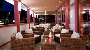 A covered outdoor seating area with wicker furniture and a central glass table. - President (San Michele al Tagliamento)