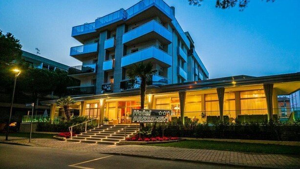 A multi-story hotel with a modern design, featuring balconies and a well-lit entrance. - President (San Michele al Tagliamento)