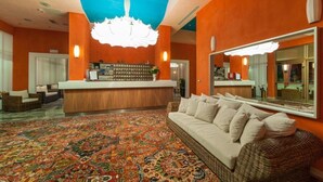 A lobby with a reception desk, a large mirror, a patterned carpet, and a sofa. - President (San Michele al Tagliamento)
