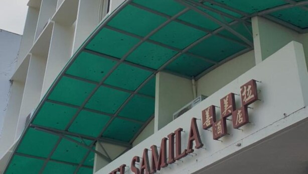 Un edificio de varios pisos con toldo verde y letrero que dice 'SAMILA HOTEL'.