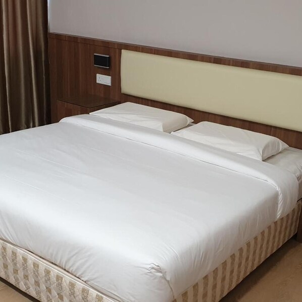A hotel room with a large bed, wooden headboard, and a small bedside table. - Hotel Samila (Alor Setar)