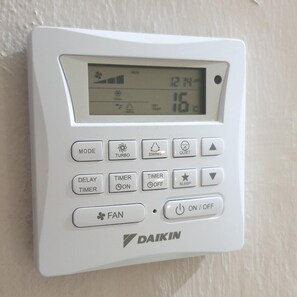 A white Daikin air conditioning unit with a digital display, control buttons, and a brand logo. - Hotel Samila (Alor Setar)