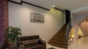 A modern living room with a brown leather sofa, a black coffee table, and a staircase with a unique design. - S Bee Hotel (Johor Bahru)