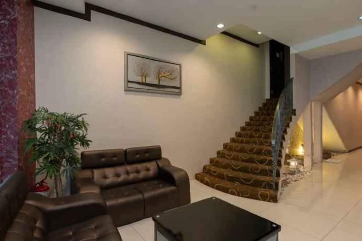 A modern living room with a brown leather sofa, a black coffee table, and a staircase with a unique design.
