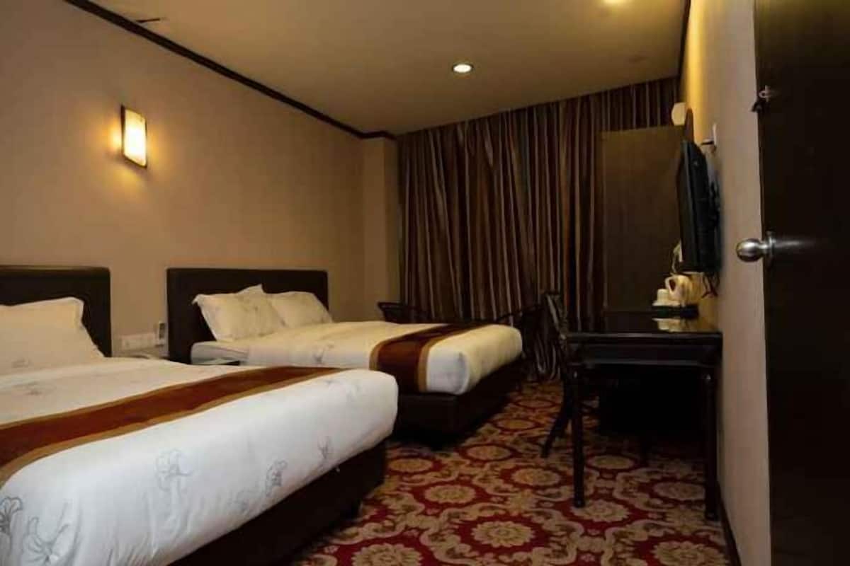 A hotel room with two beds, a desk, a chair, and a mirror.